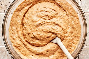 homemade pumpkin pancake batter being stirred in a glass bowl with a wooden spoon to make a cozy fall breakfast