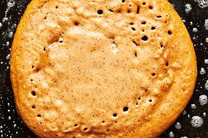 a homemade pumpkin pancake being cooked in butter in a skillet