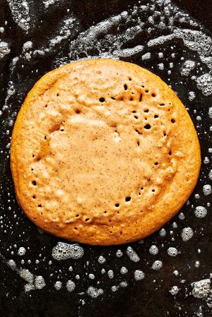 a homemade pumpkin pancake being cooked in butter in a skillet