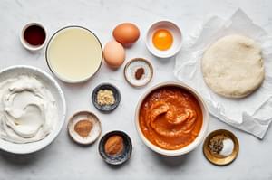 pumpkin puree, eggs, condensed milk, vanilla, cinnamon, ginger, nutmeg, cloves, pepper, salt and whipped cream in bowls