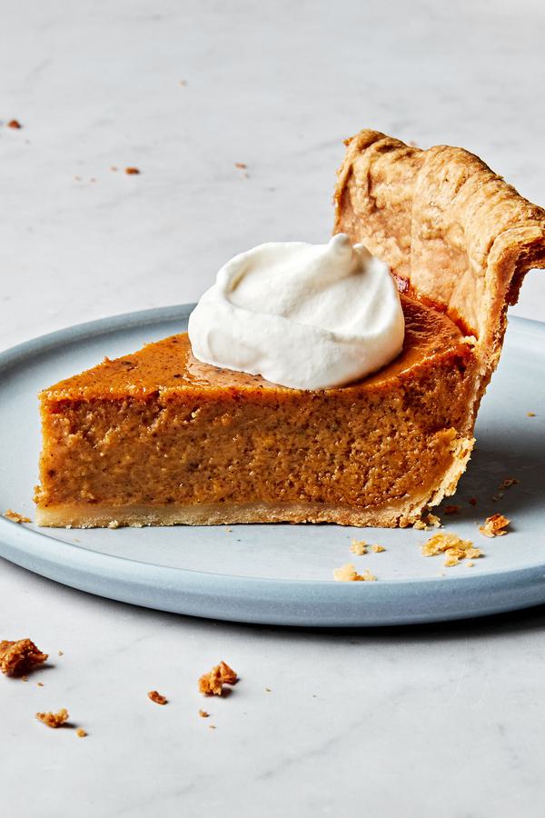 a slice of homemade pumpkin pie spiced with cinnamon, ginger, nutmeg, cloves, pepper and salt, topped with whipping cream