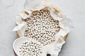 raw pie crust in a pie plate covered with parchment paper and filled with pie weights for baking