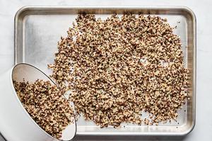 cooked quinoa being spread out on a baking sheet to cool down