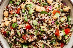 Homemade quinoa salad in a bowl, with basil, garlic, chickpeas, onion, cucumber, tomato, bell pepper, jalapeño and parsley