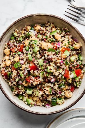 Homemade quinoa salad in a bowl, with basil, garlic, chickpeas, onion, cucumber, tomato, bell pepper, jalapeño and parsley