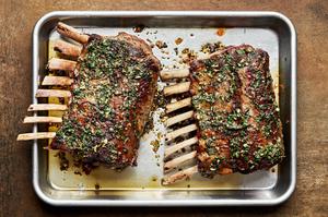 a roasted rack of lamb topped with mint sauce on a sheet pan