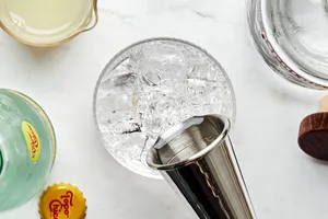 tequila being poured over ice in a glass