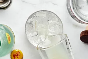 lime juice being poured into a glass with tequila