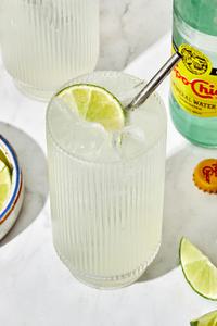 a ranch water cocktail in a glass, made with tequila, lime juice and sparkling mineral water garnished with a lime wedge