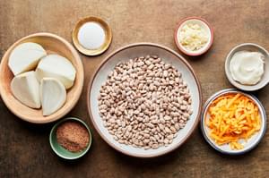 dry pinto beans, onion, lard, salt, taco seasoning, garlic and cheese in prep bowls to make homemade refried beans