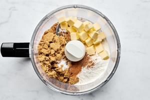 butter, brown sugar, flour, cinnamon, nutmeg, salt and oats being pulsed in a food processor