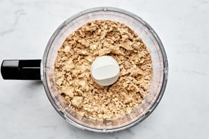 butter, brown sugar, flour, cinnamon, nutmeg, salt and oats being pulsed in a food processor