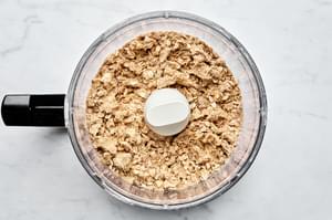 butter, brown sugar, flour, cinnamon, nutmeg, salt and oats being pulsed in a food processor