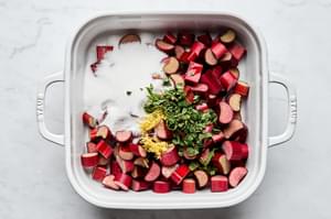 rhubarb being tossed with sugar, lemon zest, lemon juice,  and mint in a baking dish