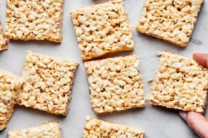 sliced homemade rice crispy treats on the counter made with butter, marshmallows, vanilla and rice krispie cereal