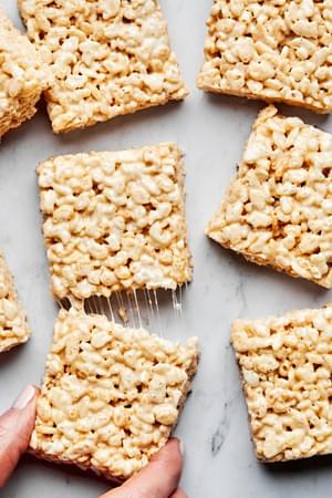 sliced homemade rice crispy treats on the counter made with butter, marshmallows, vanilla and rice krispie cereal