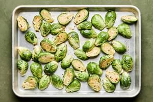 brussels sprouts tossed with sweet fish sauce dressing on a baking sheet ready to be roasted