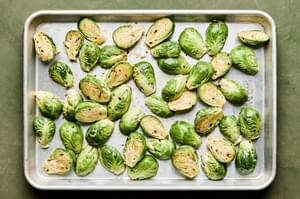 brussels sprouts tossed with sweet fish sauce dressing on a baking sheet ready to be roasted