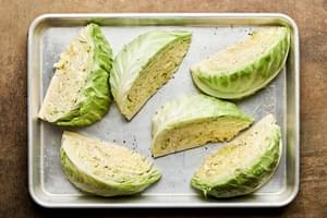 cabbage wedges tossed with olive oil, garlic, salt and pepper on a baking sheet ready to be roasted until golden and tender