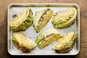 Roasted cabbage wedges on a baking sheet seasoned with garlic, salt and pepper