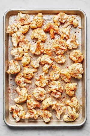 cauliflower florets tossed with olive oil, salt, garlic powder, smoked paprika and red pepper flakes on a baking sheet
