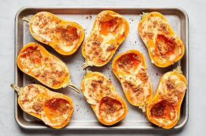 honeynut squash topped with butter, brown sugar, cinnamon, salt and cayenne on a baking sheet