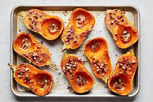 roasted honeynut squash seasoned with brown sugar, cinnamon, salt and cayenne topped with pecans on a baking sheet
