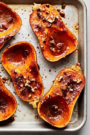 roasted honeynut squash seasoned with brown sugar, cinnamon, salt and cayenne topped with pecans on a baking sheet
