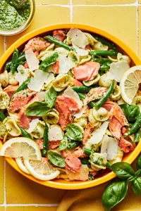 salmon pasta with homemade pesto tossed with green beans and lemon zest and sprinkled with parmesan cheese in a serving bowl