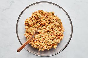 salmon, spices, Dijon, lemon juice, chives, mayonnaise, egg & breadcrumbs being mixed together with a fork in a bowl