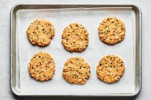 raw salmon patties on a parchment lined baking sheet made with spices, Dijon, lemon juice, chives, mayo, egg & breadcrumbs
