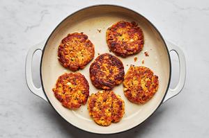 homemade salmon patties being cooked in vegetable oil in a skillet