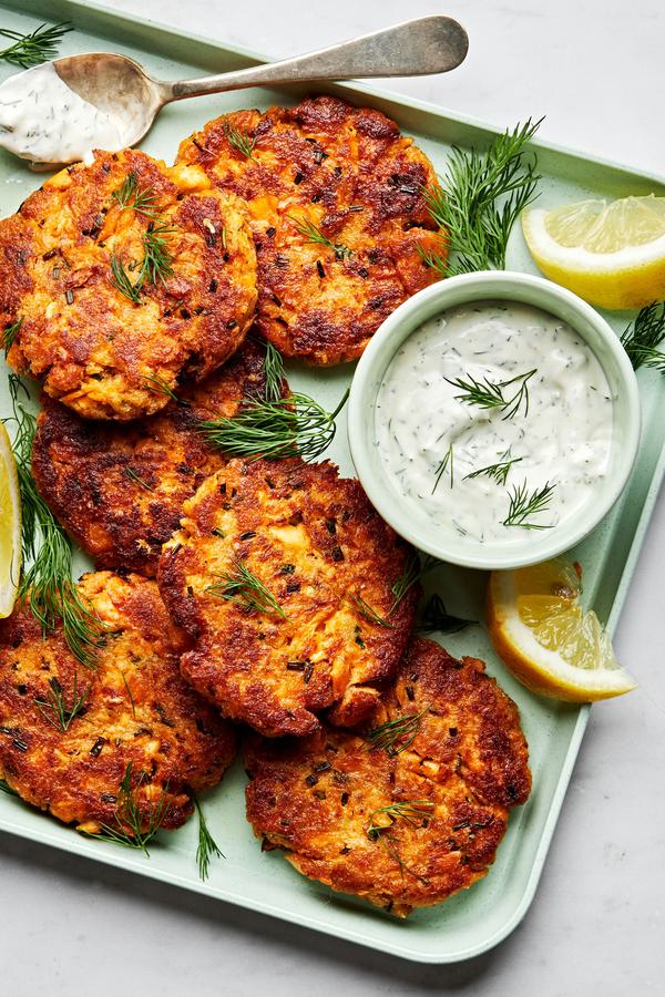 homemade salmon patties on a platter with a bowl of homemade dill dip and lemon wedges for serving