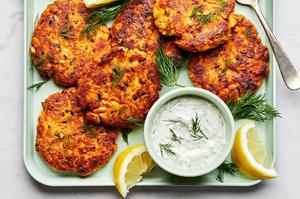 homemade salmon patties on a platter with a bowl of homemade dill dip and lemon wedges for serving