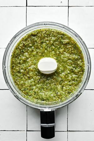 homemade salsa verde in a food processor made with charred tomatillos, onion &jalapeños, & cilantro and salt