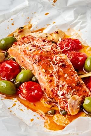 A perfectly cooked salmon en papillote, served with a rich, velvety tomato butter, with tomatoes, green olives and capers