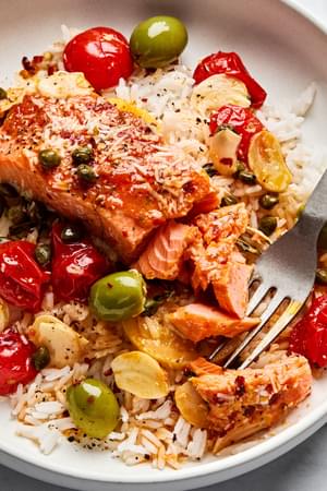 A perfectly cooked salmon en papillote, served with a rich, velvety tomato butter served over rice and topped with Parmesan