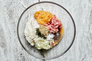 ingredients for sausage rolls in a large glass bowl including breadcrumbs, eggs, cheese, sausage, sage and pear chutney
