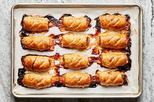twelve sausage rolls baked on a rimed baking sheet