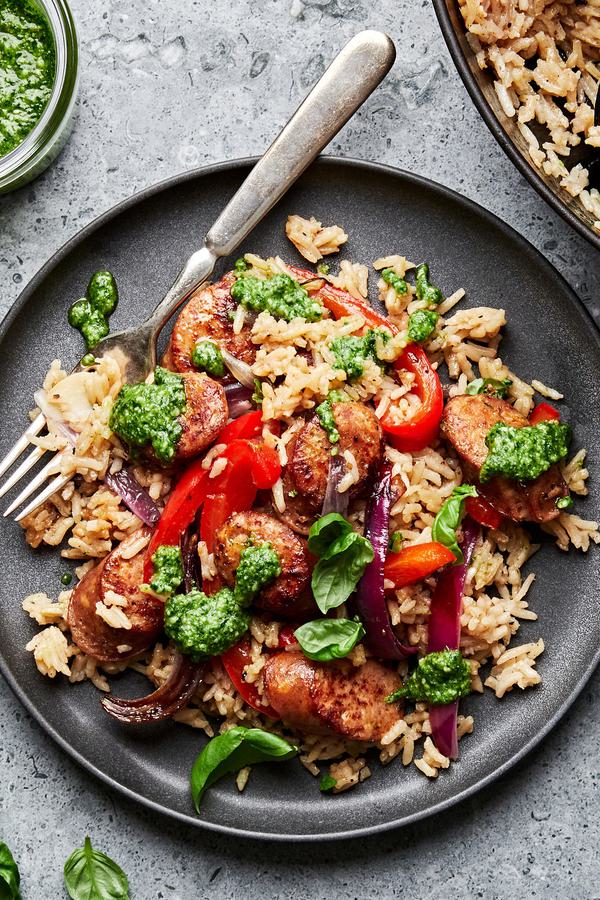 homemade sausage and rice skillet made with italian chicken sausage, peppers, onions and basil on a plate topped with pesto