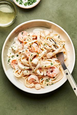 a bowl of homemade seafood fettuccine alfredo made with shrimp and scallops, sprinkled with parsley