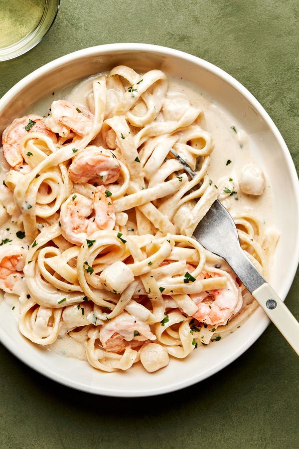 a bowl of homemade seafood fettuccine alfredo made with shrimp and scallops, sprinkled with parsley