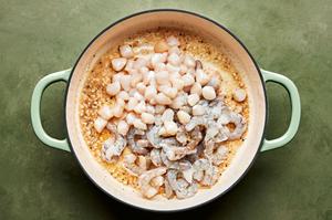 shrimp and scallops added to a skillet with butter, garlic, garlic powder, nutmeg, salt and pepper