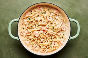 homemade seafood fettuccine alfredo in a skillet made with butter, cream, garlic, garlic powder, nutmeg, salt, pepper  & Parm
