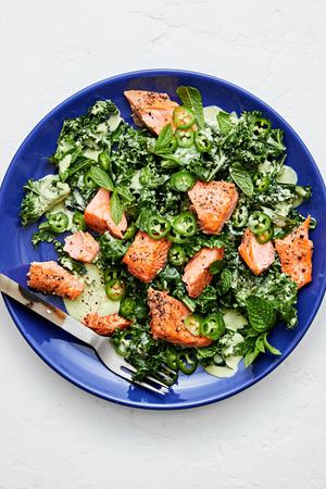 Serrano Mint Kale Salad with Salmon garnished with serrano peppers and parmesan in a serving bowl