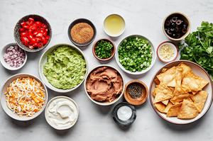 guacamole, refried beans, shredded cheese, sour cream, tomatoes, olives, green onion and cilantro in prep bowls