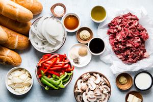 ingredients laid out for sheet pan Philly cheese steaks mushrooms, red and green bell peppers, provolone, cream, mustard