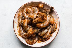 raw shrimp in a bowl marinated in taco seasoning and olive oil