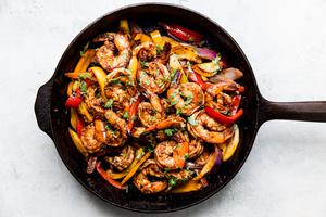 shrimp fajitas in a cast iron skillet with cilantro and bell peppers