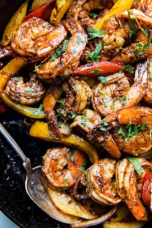 shrimp fajitas in a cast iron skillet with cilantro and bell peppers